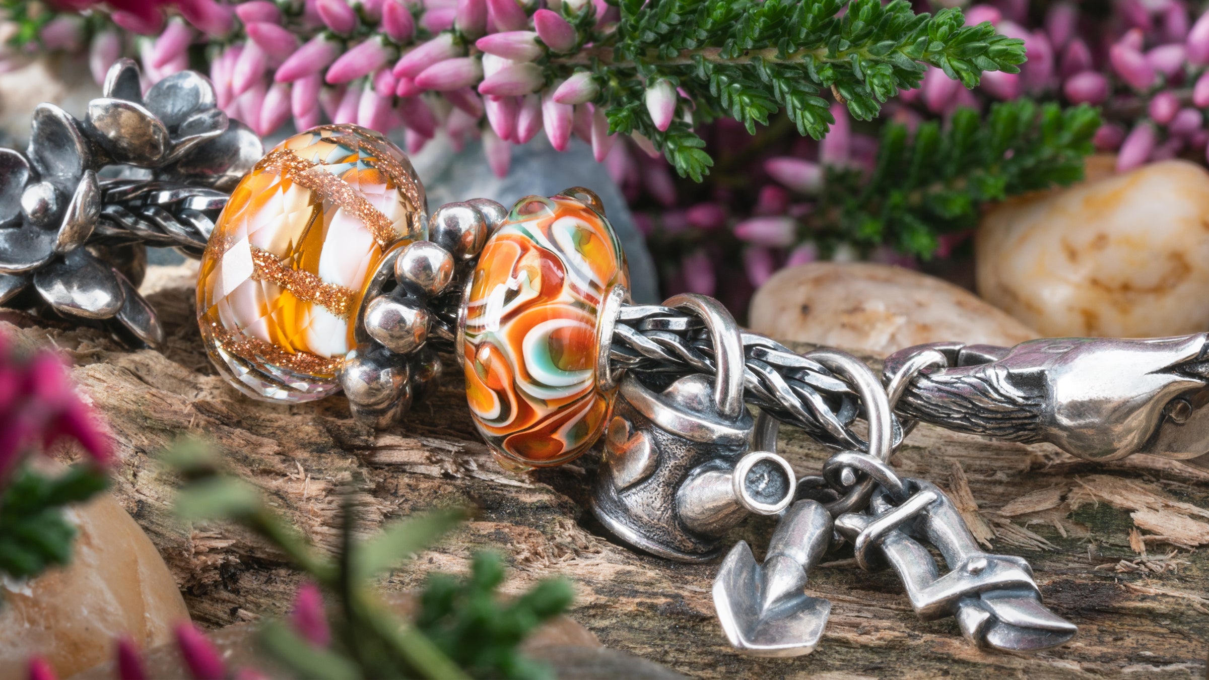 Armband mit Beads der Frühlingskollektion Blühendes Leben, auf einem Baumstamm liegend. Im Hintergrund Blumen