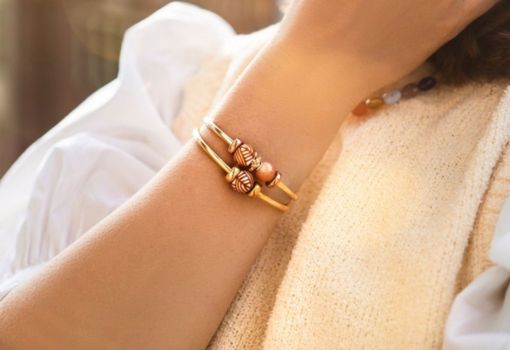 Nahaufnahme von zwei vergoldeten Armreifen, verziert mit Barrel Beads