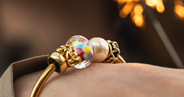 Happy Bead 2024 an einer vergoldeten Armspange am Handgelenk eines Models