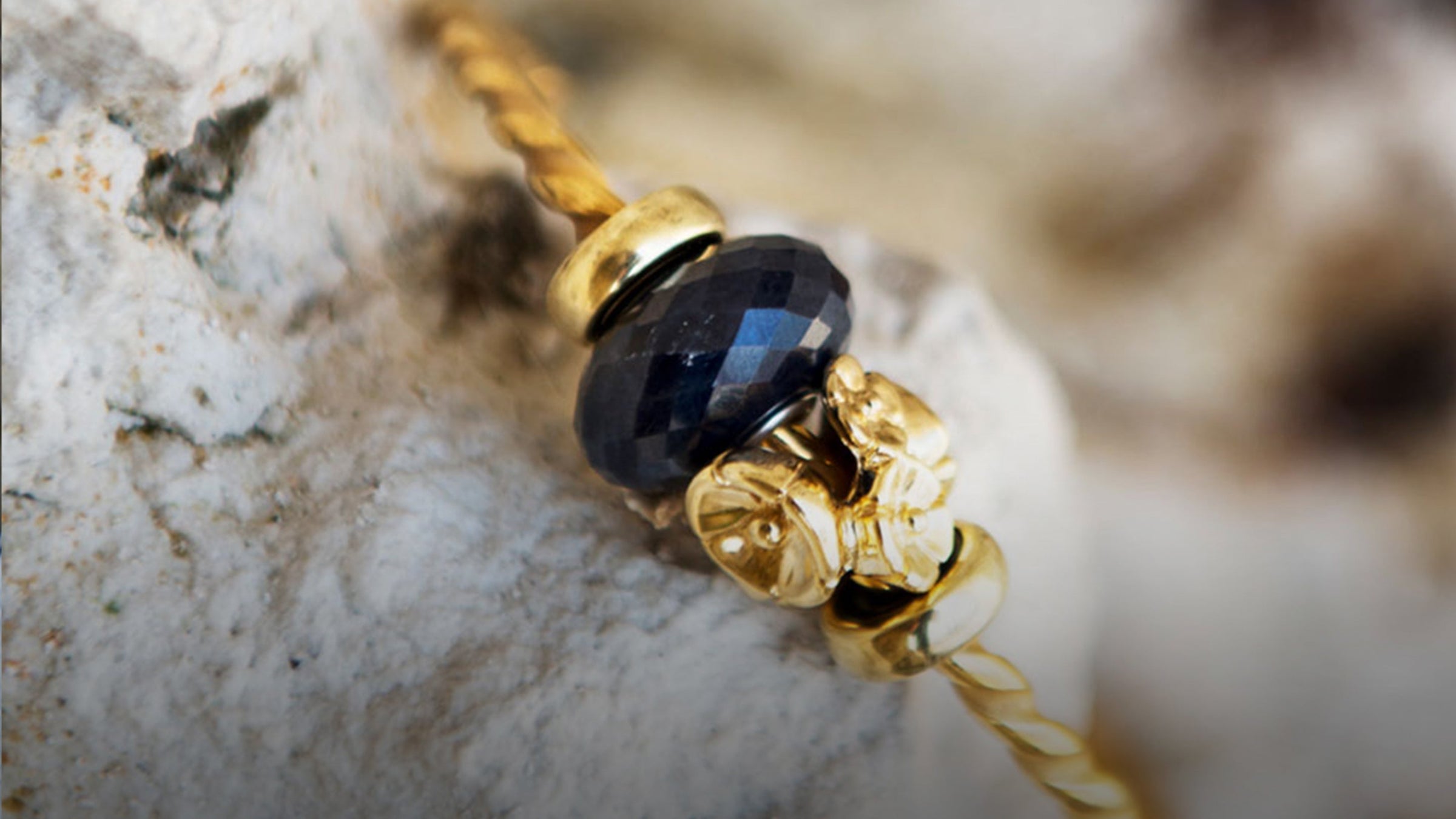 Gedrehte Goldarmspange mit Onyxbeads und Blumenbeads in Gold