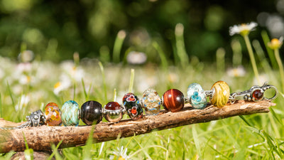 Trollbeads auf einem Ast liegend auf einer Wiese