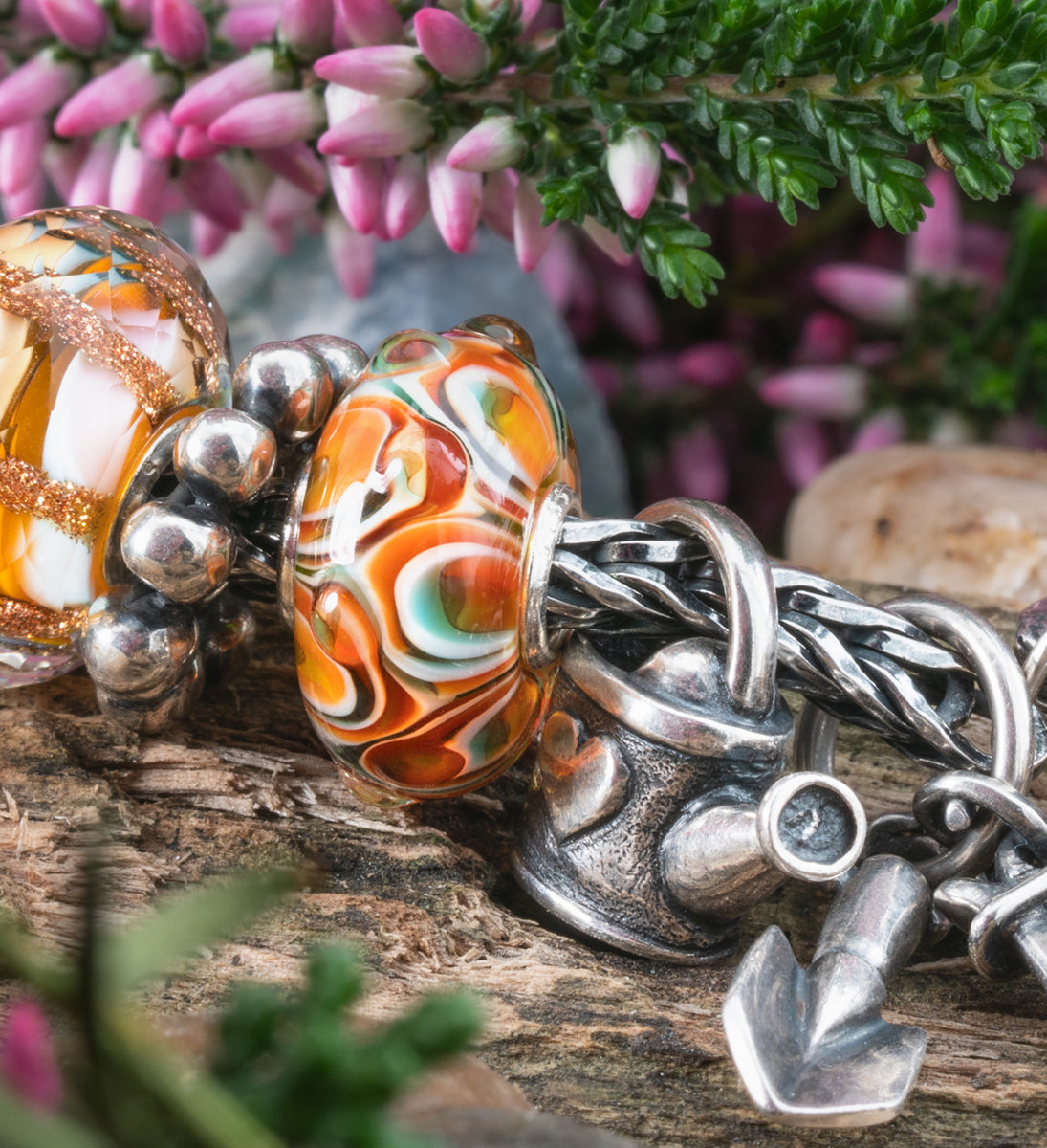 Armband mit Beads der Frühlingskollektion Blühendes Leben, auf einem Baumstamm liegend. Im Hintergrund Blumen