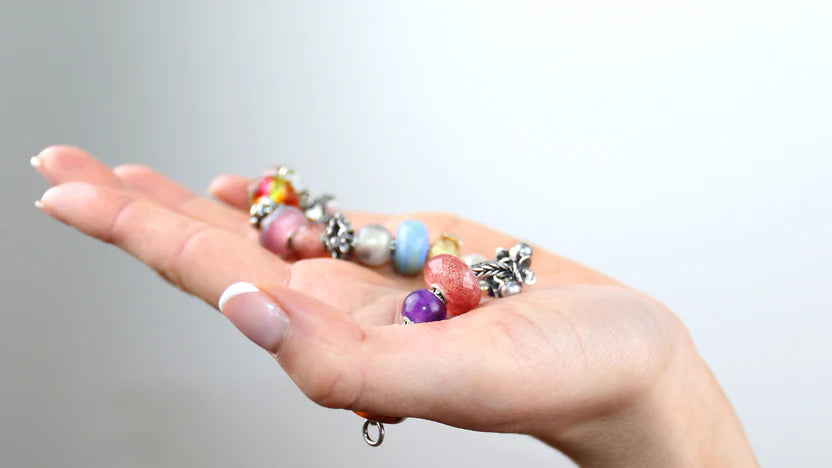 Hand hält ein Silberarmband voller Beads
