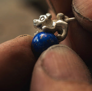 Schmuck-Charme einer Hundefigur auf einer Lapislazuli Kugel, in der Herstellung, mit komplizierten Details und lebendigen Farben in einer fesselnden Darstellung der Handwerkskunst