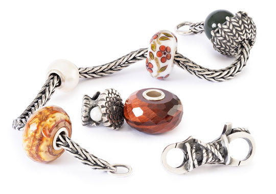 Armband mit verschiedenen Beads in warmen Farben auf weißem Hintergrund