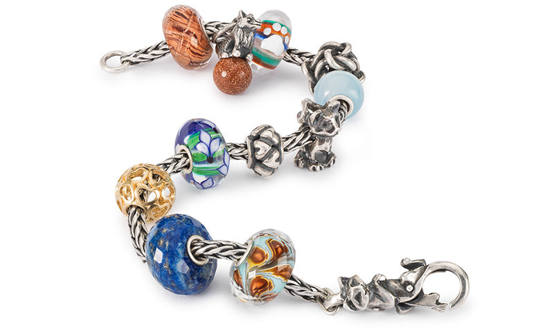 Trollbeads Armband mit einer Mischung aus Beads in Gold, Silber und Edelsteinen, ein Glasbeads mit einem kleinen Pfotenabdruck und Beads mit Katzen und einem Hund, die die geschätzte Bindung und Zuneigung zwischen Haustieren und ihren Besitzern darstellen.