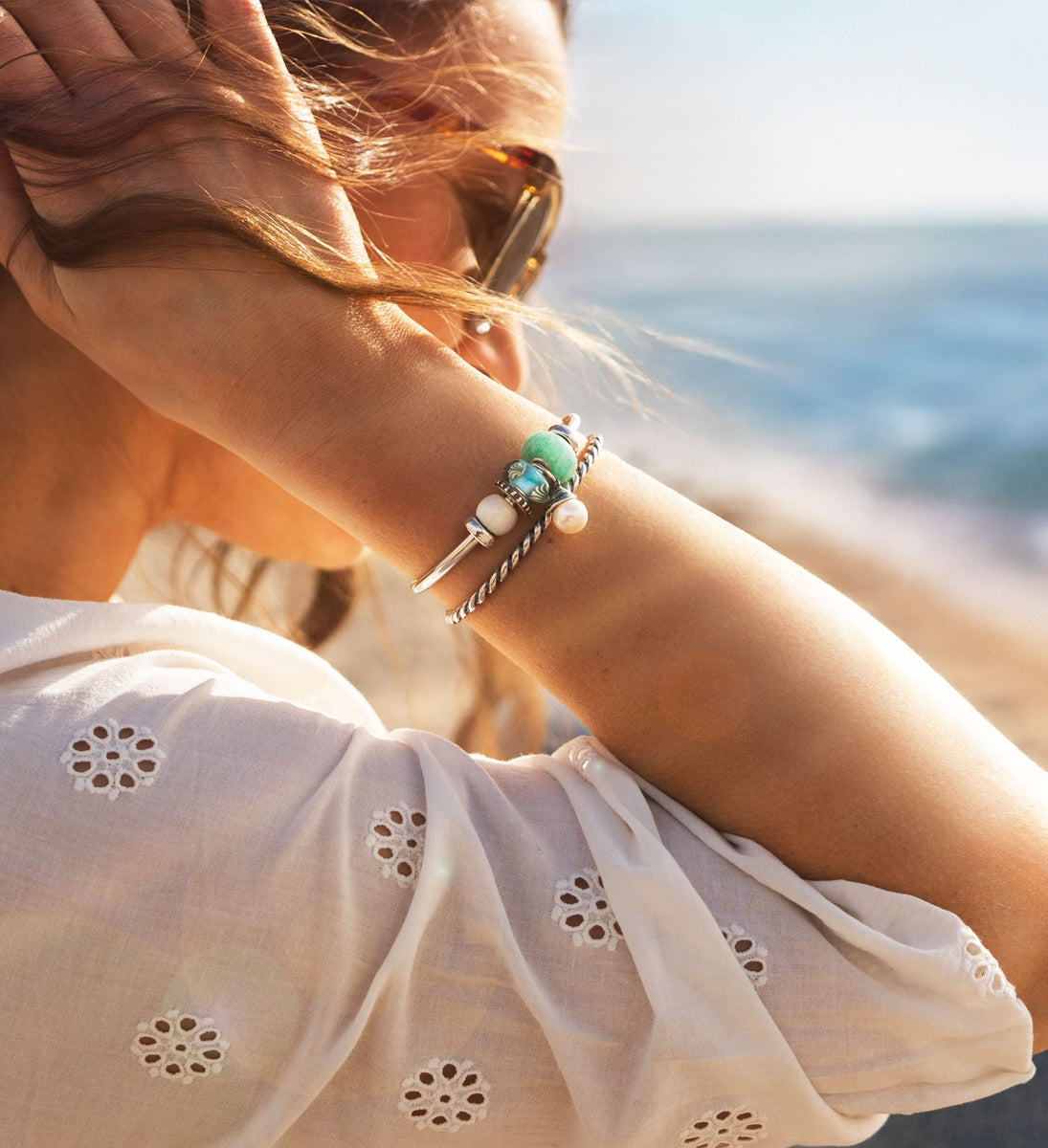 Modell mit silbernen Armreifen und bunten Sommerbeads am Strand, Schätze der Gezeiten Sommerkollektion 2025