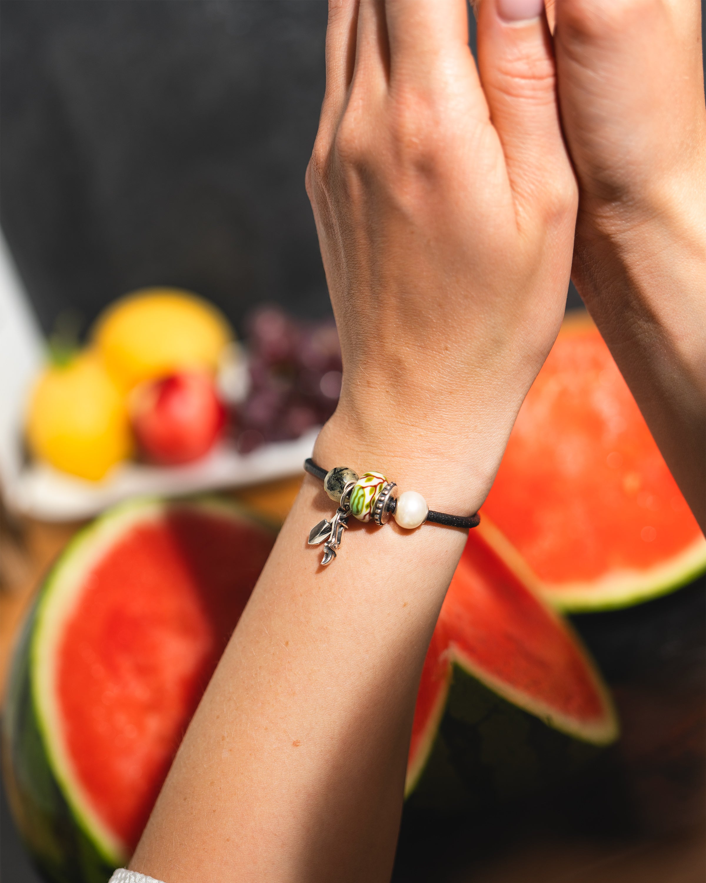 Model mit Leder Armband mit Beads. Im Hintergrund eine aufgeschnittene Melone