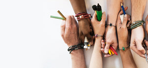 6 Hände, wobei jedes Handgelenk ein Trollbeads-Armband und Beads trägt. Sie haben Künstlerbedarf in den Händen für den People's Bead Design Wettbewerb