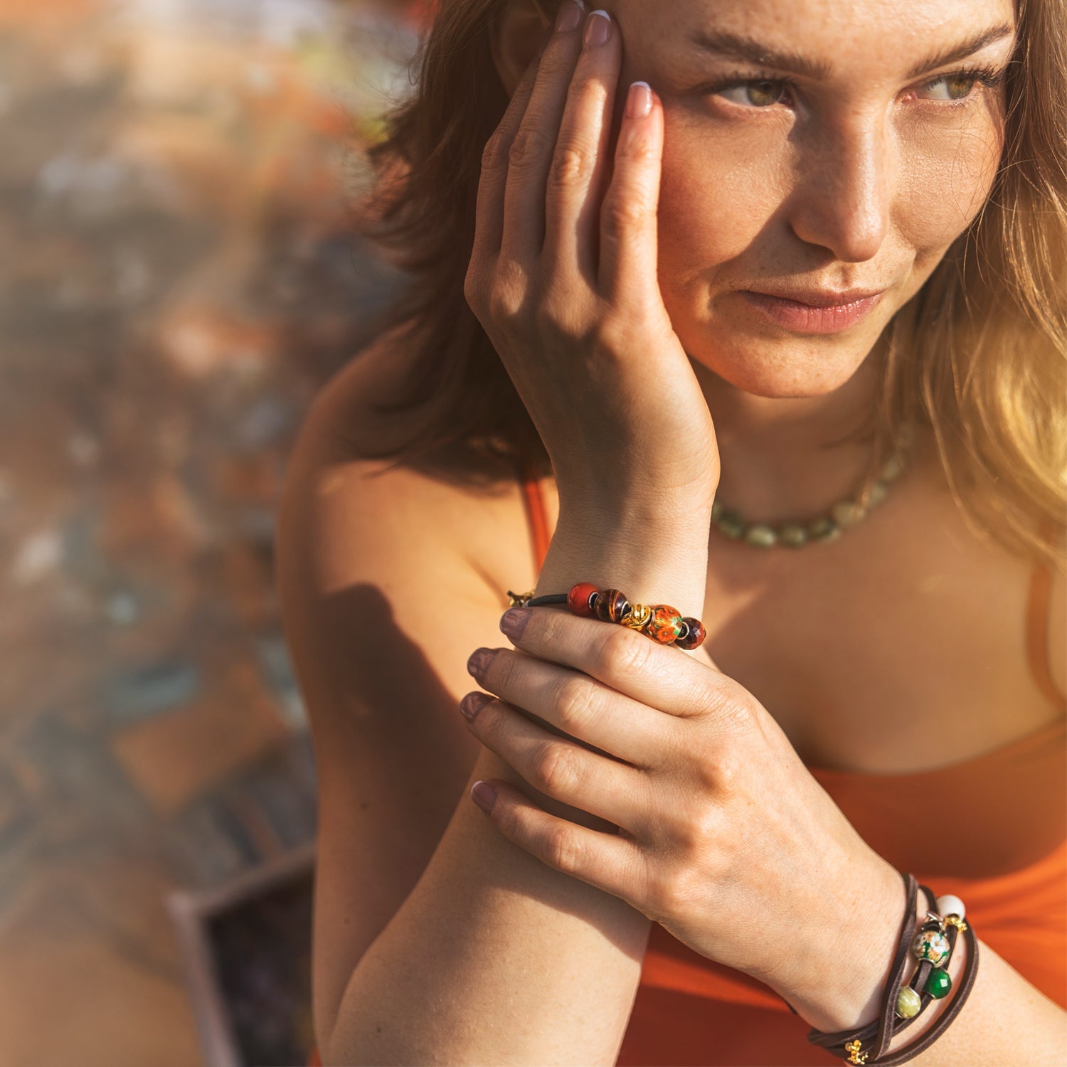 Eine Frau mit bunten Armbändern vor einem unscharfen Hintergrund im Freien