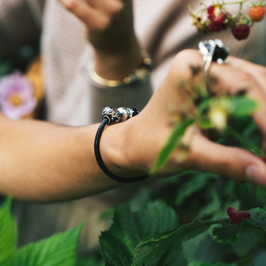 Model, das Beeren pflückt und dabei ein Lederarmband mit Beads trägt