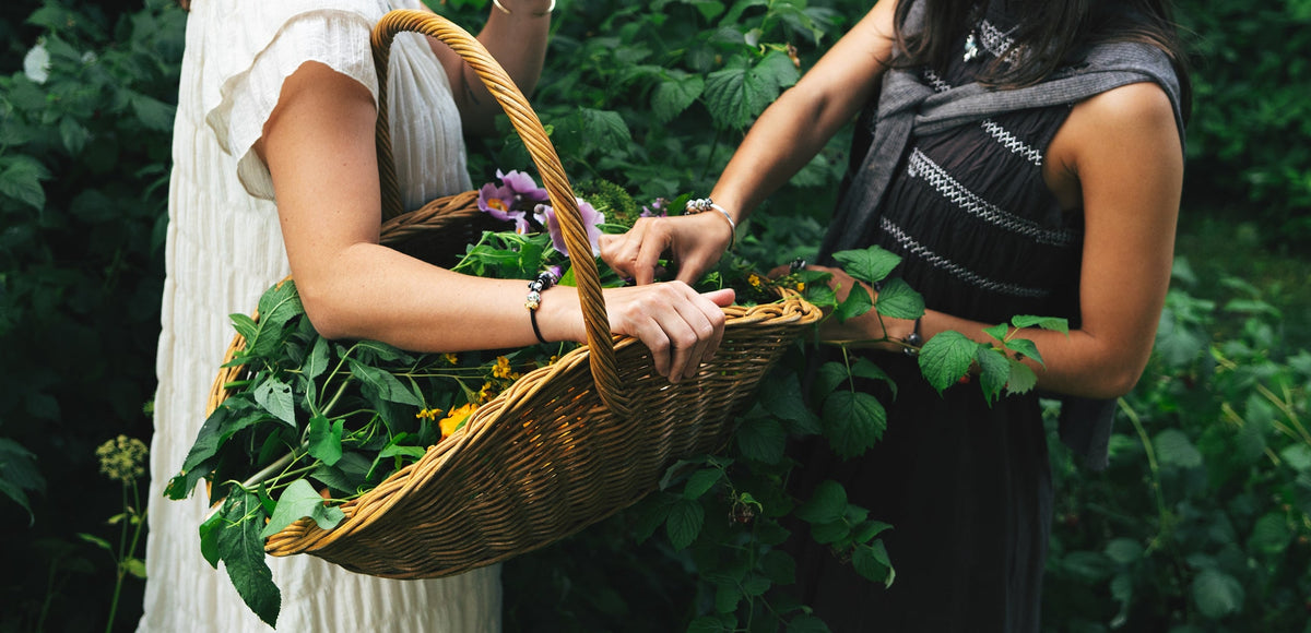 Zwei Models, die Armbänder mit Beads tragen, während sie in der Natur Blumen pflücken