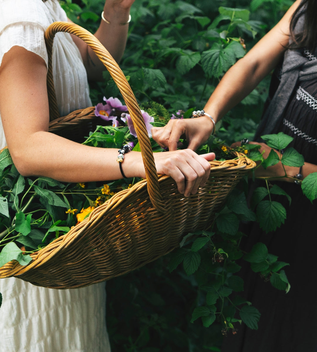 Zwei Models, die Armbänder mit Beads tragen, während sie in der Natur Blumen pflücken