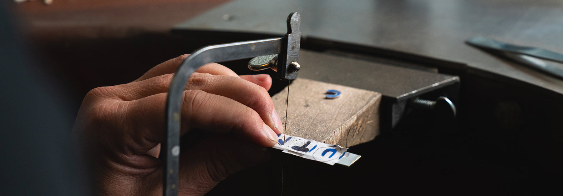 Buchstaben werden in eine Silberplatte gesägt, wobei handgemalte Buchstaben als Orientierungshilfe dienen